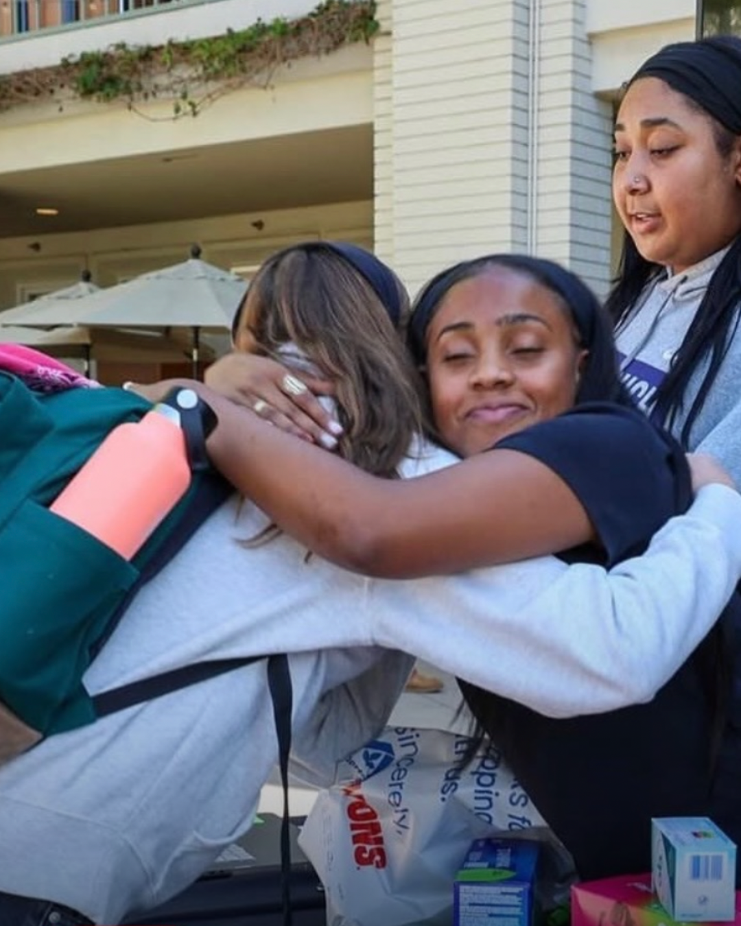 High school student Amirah hugs another volunteer during her donation drive for menstrual care products supporting women and girls served by St. Joseph Center.