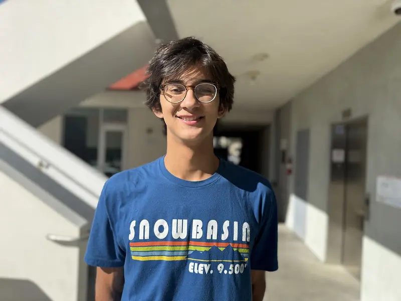 Mateo, a youth volunteer at St. Joseph Center, standing indoors and smiling at the camera.