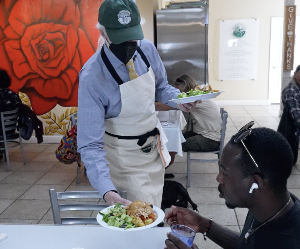 Kevin McArdle serves a meal to a guest at St. Joseph Center's Bread & Roses Café.