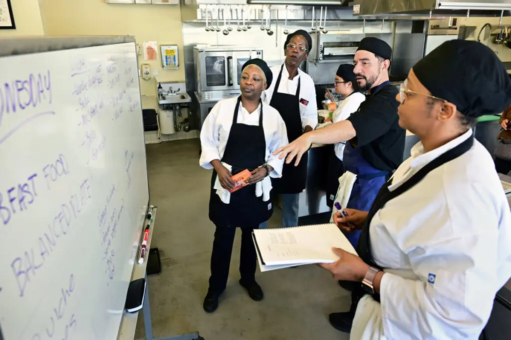 Chef Tomas Hernandez explains meal preparation steps to students in St. Joseph Center’s culinary training kitchen.
