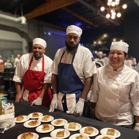chefs in front of table with food at an event