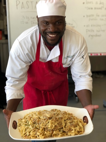 Male chef holding a plate of pasta