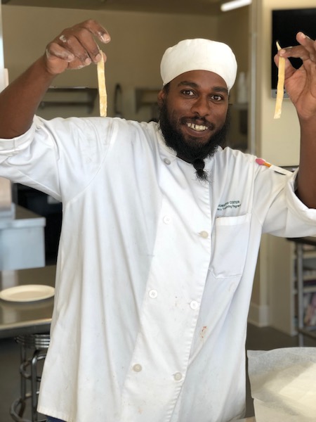Chef student holding up pasta