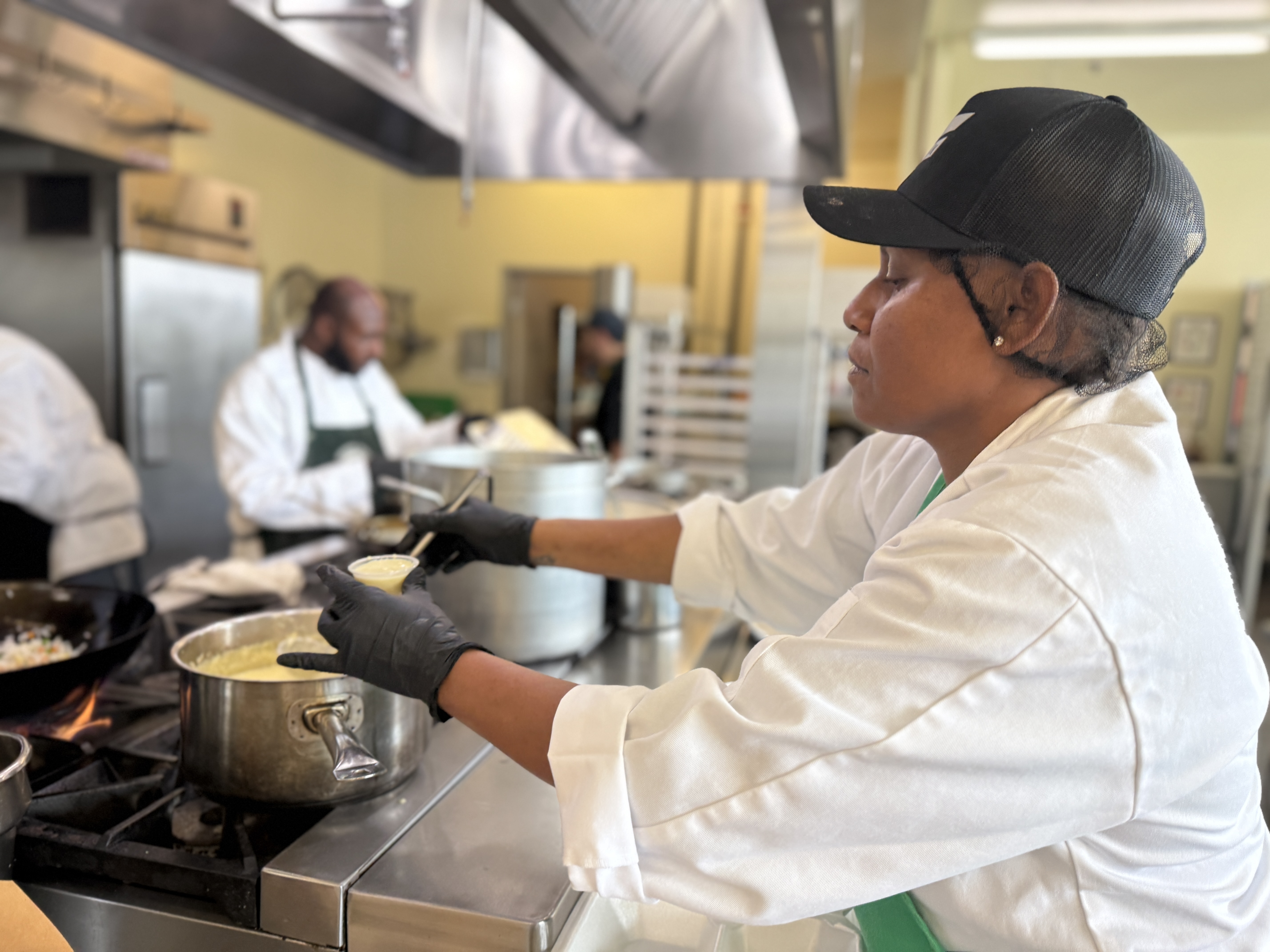 Chef stirring sauce on stovetop at Bread & Roses kitchen.