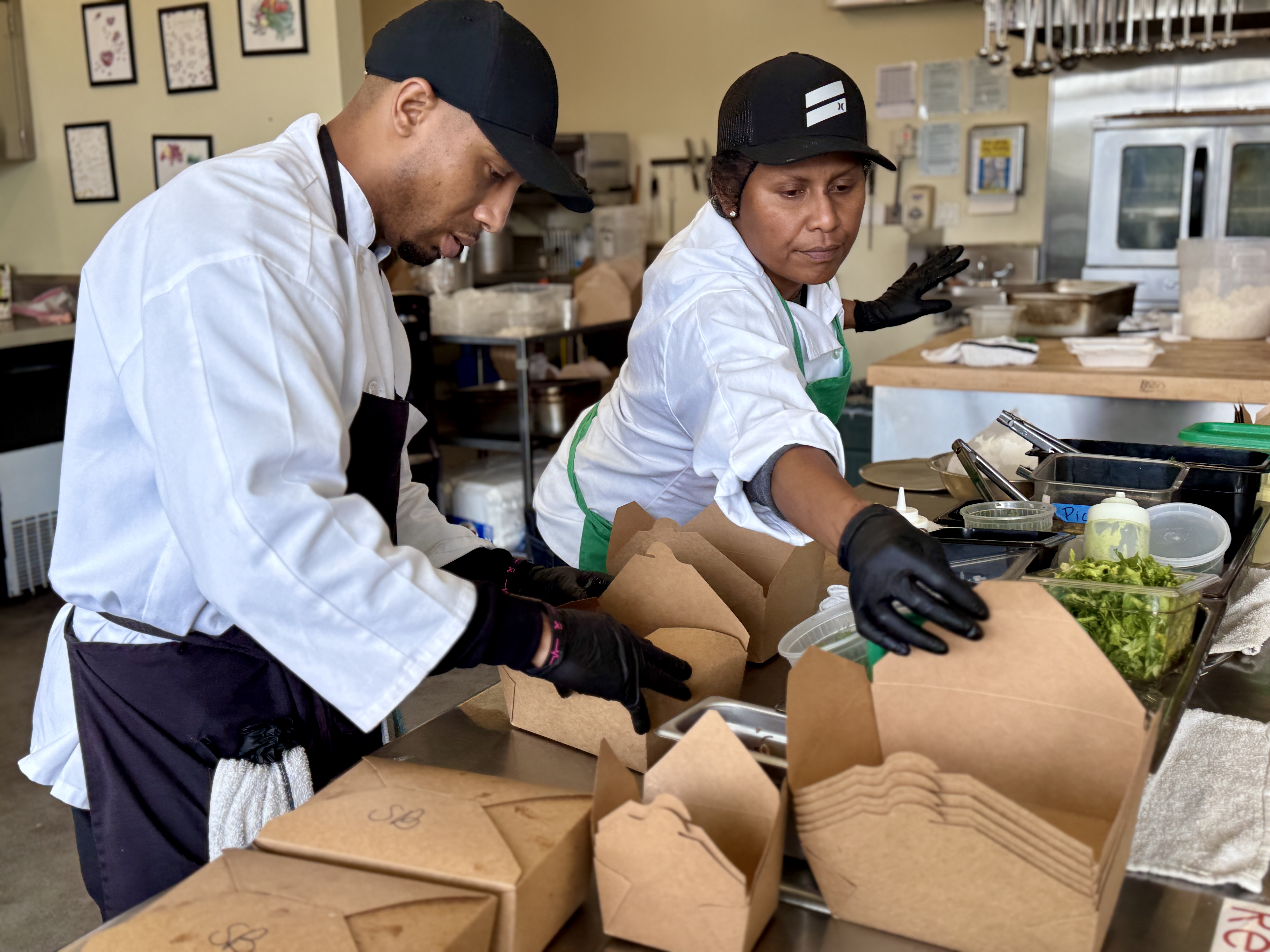 Students packing to-go boxes with fresh meals.