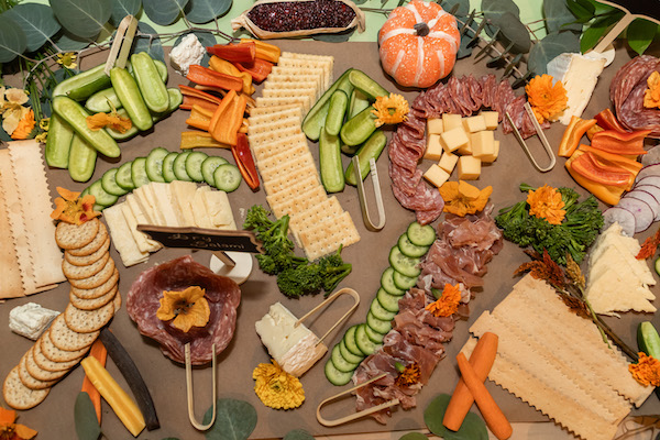 A colorful grazing table with vegetables, cheeses, meats, and small pumpkins arranged for the ChefsGiving event.