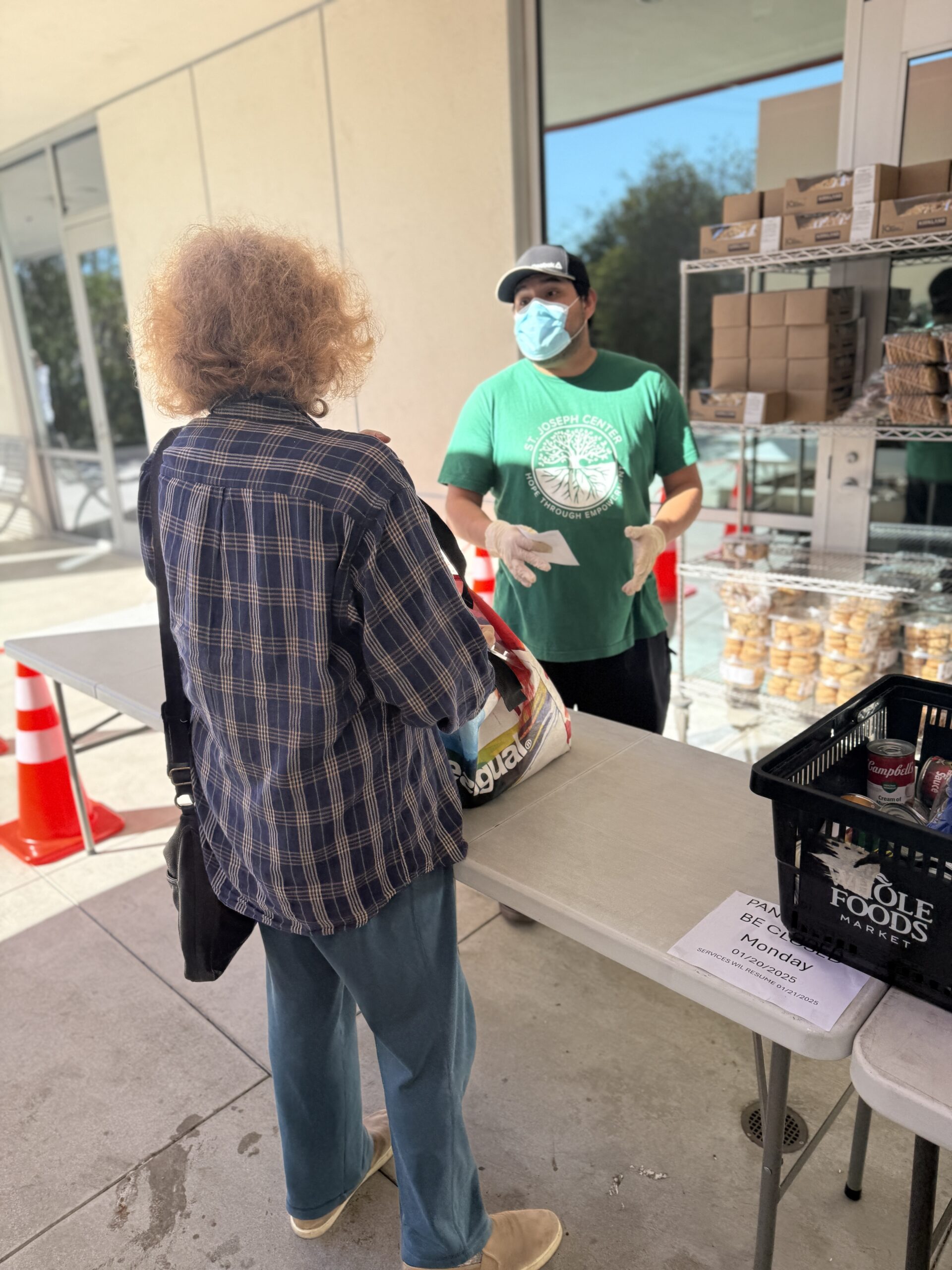 Volunteers assisting a client with groceries at the distribution table.