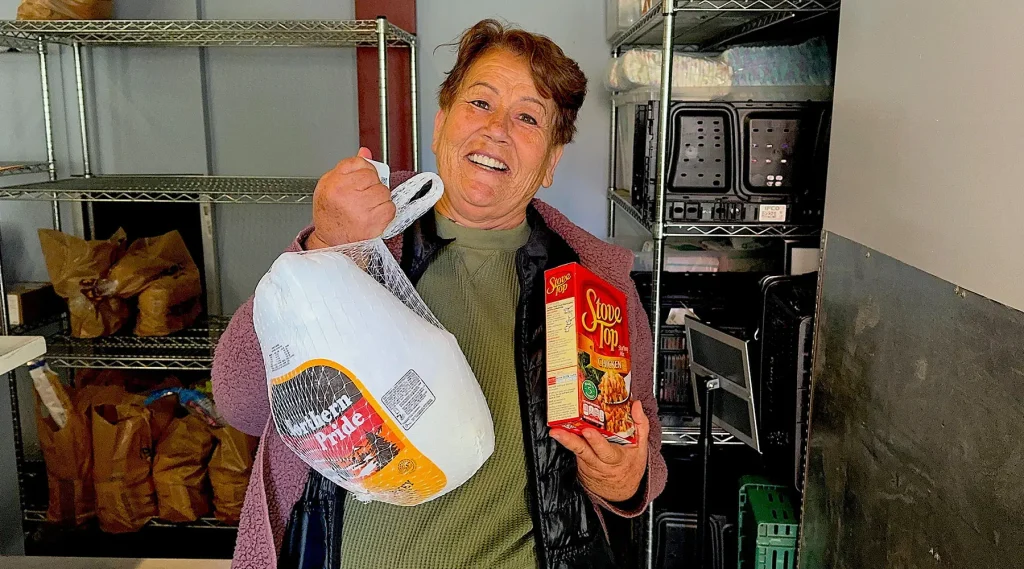 A woman holding a donated turkey from the food pantry.