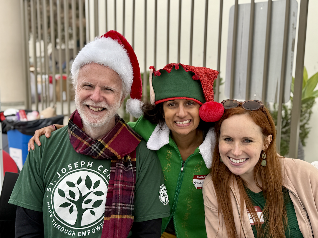 Deacon Kevin McCardle smiling with St. Monica Catholic Community volunteers at a holiday event