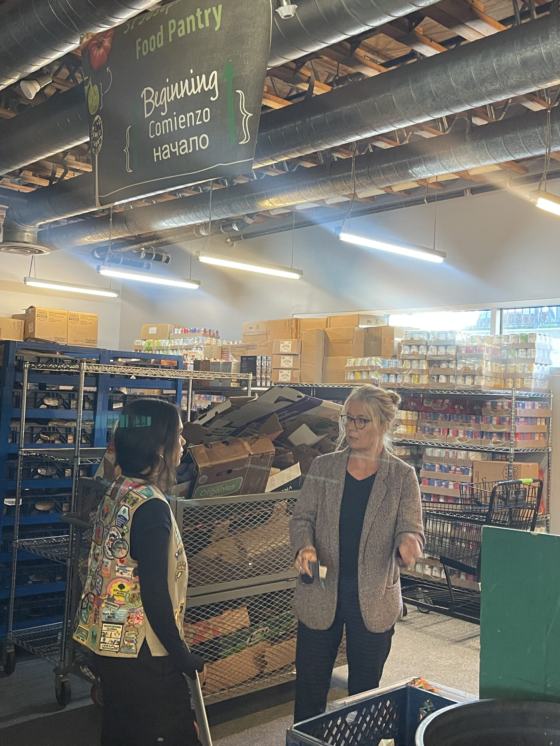 Sienna speaks with Sharon Plunkett inside the Bread and Roses Food Pantry while sharing her Breathe Easy project