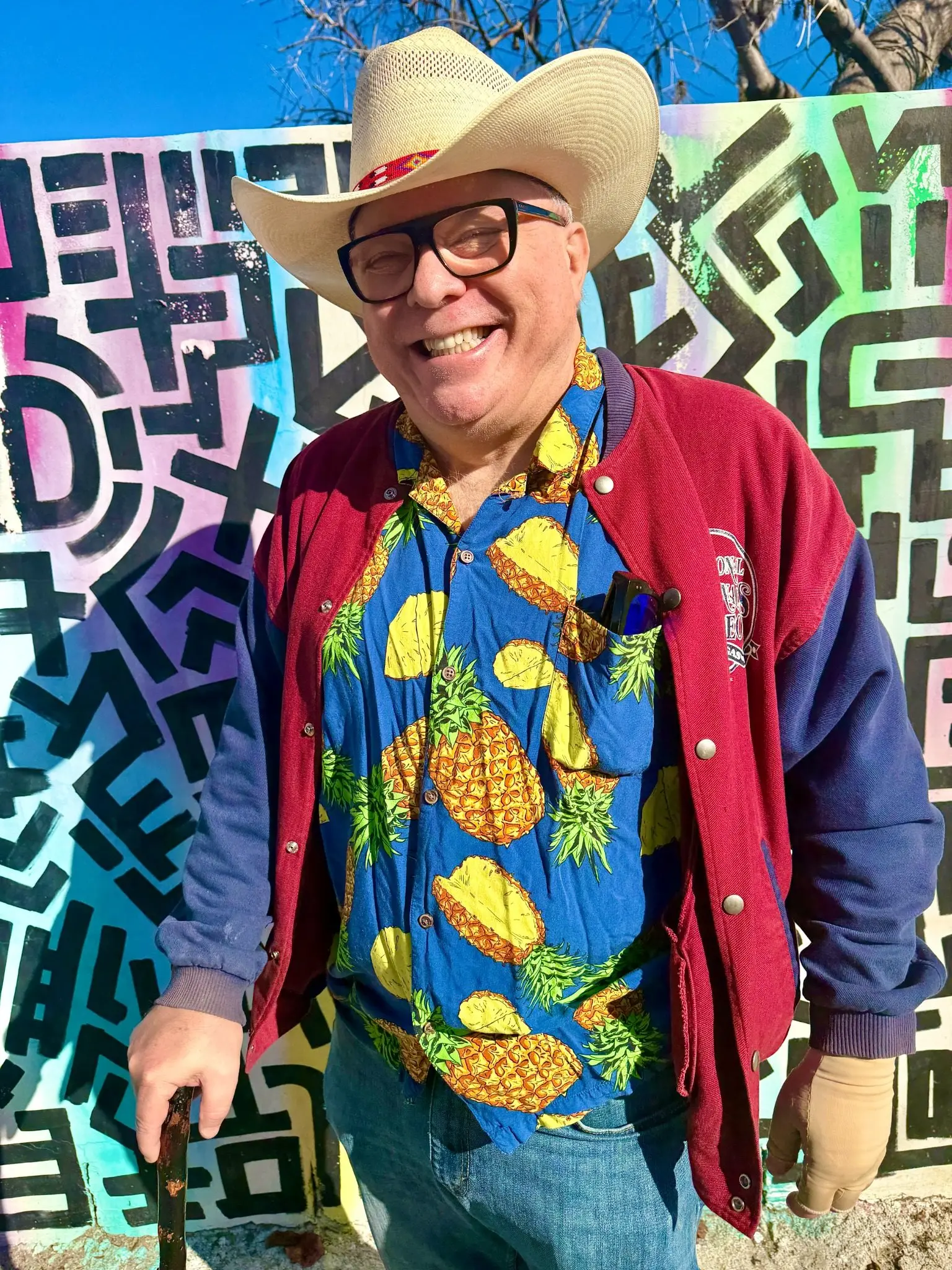 Marc Royston smiling outdoors in front of a colorful mural.